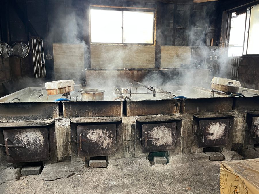 平釜で薪を焚いて海水を煮詰める製造風景