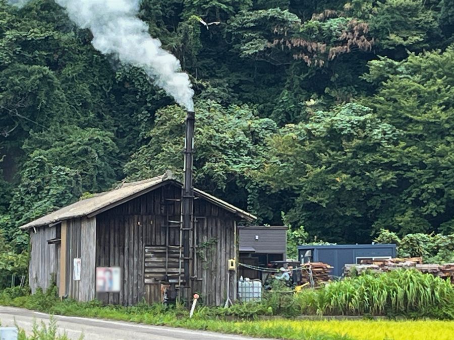 笹川流れの塩 新潟県内の製造拠点の建物と煙突から出る煙