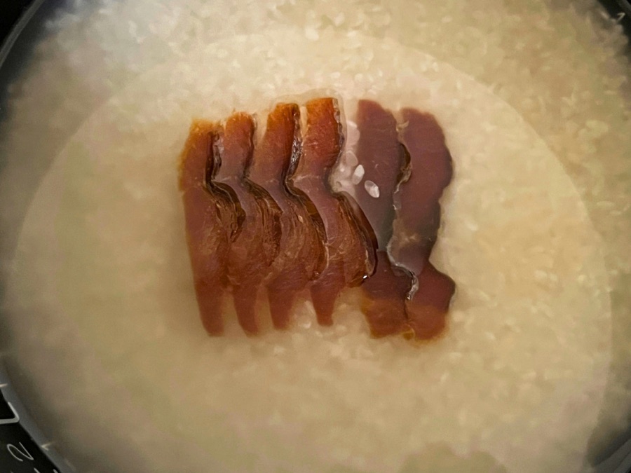 鮭の酒びたしと刻み生姜をのせて炊く前の炊飯器